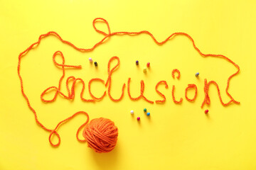 Word INCLUSION made of yarn with pawns on yellow background