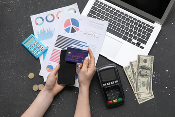 Female hands with credit card, smartphone, laptop, and charts on black background, House rent concept