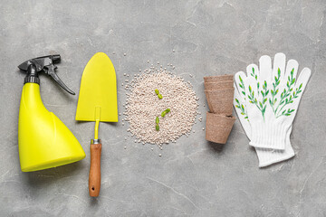 Gardening tools, peat pots and granular fertilizer with seedlings on grey grunge background