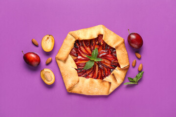 Delicious plum galette with mint and almond on purple background