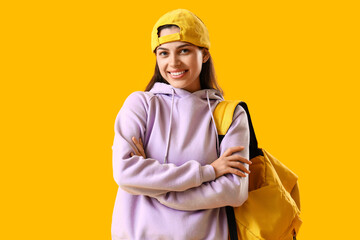 Young woman in lilac hoodie with backpack on yellow background