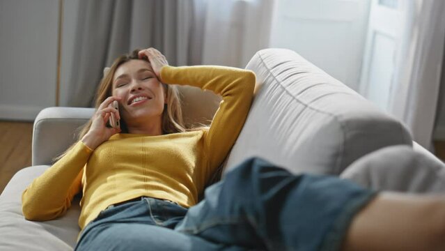 Positive lady speaking cellphone call chilling home zoom on. Woman laying sofa