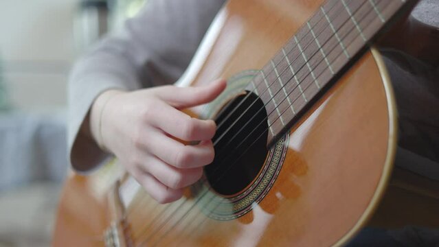 Young girl learning how to play a guitar at home