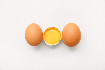 Cracked and whole chicken eggs on white background