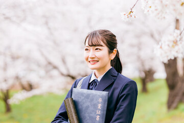 満開の桜の下で卒業証書を持つ高校生・女子高生（卒業生・卒業式・卒業）
