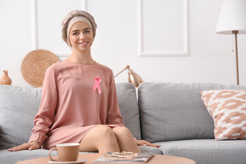 Young woman after chemotherapy with ribbon at home. Breast cancer awareness concept - obrazy, fototapety, plakaty