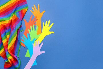 Paper hands with rainbow fabric on blue background. LGBTQ concept