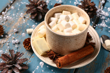 Cup of hot chocolate with marshmallows, different spices and beautiful decorations on blue wooden table