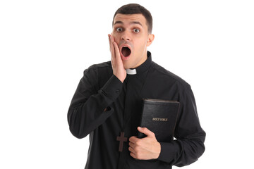 Shocked young priest with Holy Bible on white background