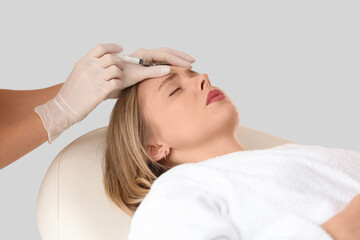 Fototapeta premium Young woman receiving forehead anti-aging injection, cosmetic procedure for wrinkle reduction and skin rejuvenation, this aesthetic procedure aims for skin rejuvenation and a youthful appearance