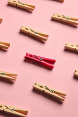 One pink clothespin among wooden ones on color background. Concept of uniqueness