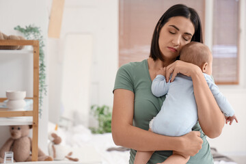 Sad young woman with her baby suffering from postnatal depression in bedroom