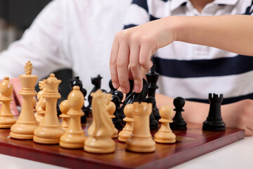 Little child playing chess at table, closeup