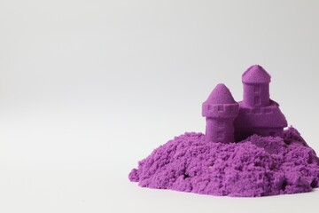 Castle made of purple kinetic sand on white background. Space for text