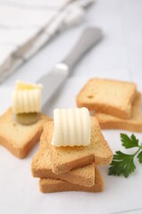 Tasty butter curls, knife and pieces of dry bread on white table, closeup