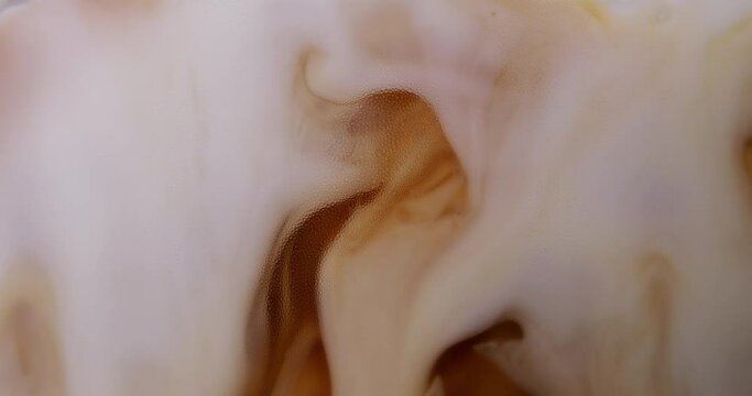 4K footage horizontal video front view SLO MO CU, Cappuccino iced coffee mug where milk is being mixed with coffee, coffee art concept.	