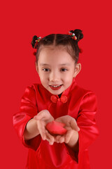 Cute little Asian girl with fortune cookie on red background. Chinese New Year celebration
