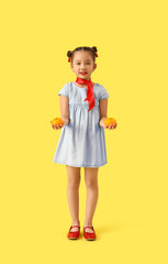 Cute little Asian girl with mandarins on yellow background. Chinese New Year celebration