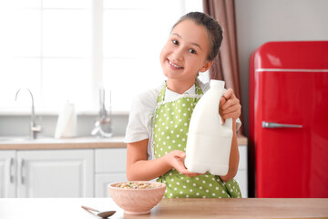 Cute little girl with bottle of milk and cereal rings at home