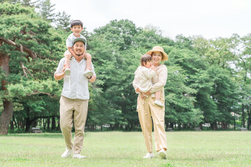 Obraz premium 夏休みに公園を手を繋いで歩く家族・ファミリー（レジャー・アウトドア・ピクニック・キャンプ・思い出） 