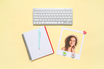Photo of beautiful woman with computer keyboard, notebook and pen on yellow background. Concept of online dating
