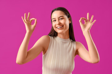 Young woman showing OK on purple background
