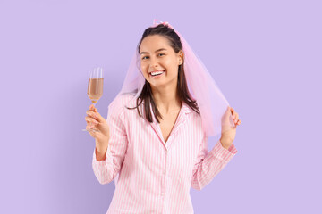 Happy bride in pajamas with glass of champagne on lilac background. Hen Party