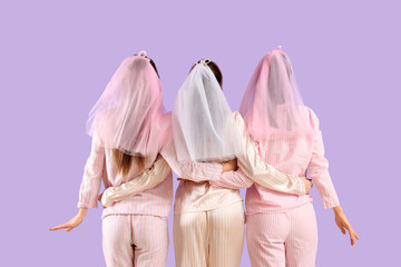Young woman with her bridesmaids in pajamas hugging on lilac background, back view. Hen Party