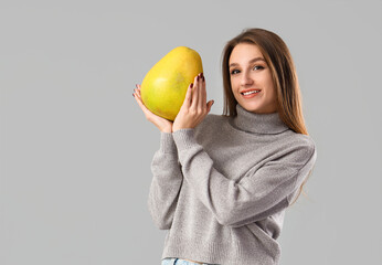 Smiling young woman with pomelo on light background