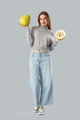 Young woman with pomelo on light background