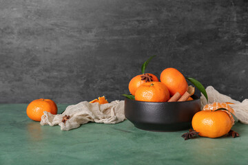 Bowl of sweet mandarins with cinnamon and star anise on green table