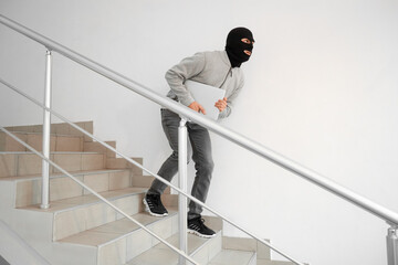 Male thief with laptop escaping in stairway