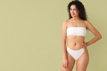 Beautiful young happy African-American woman with stretch marks on her body against green background