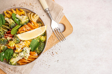 Delicious fusilli pasta with broccoli and lemon piece in bowl on light background