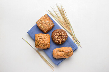 Napkin with delicious buns and wheat ears on white background