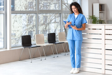 Female African-American medical intern with clipboard in clinic