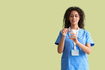 Female African-American medical intern with syringe on green background
