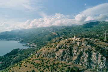 Church of St. Sava on a rocky mountain overlooking the green mountain range above the Bay of Kotor. Montenegro. Drone