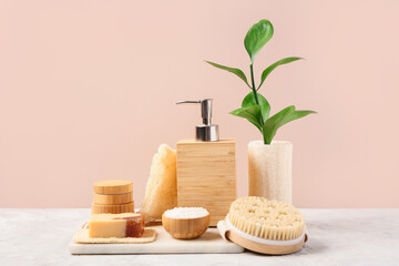 Composition with soap, sea salt and brush on table near pink wall. Bath accessories