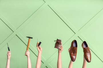Female hands with shoes and craft tools on green wooden background. Shoe repair concept