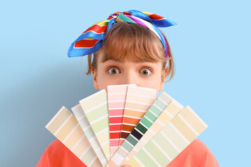 Young woman with paint color palettes on blue background. Repair concept
