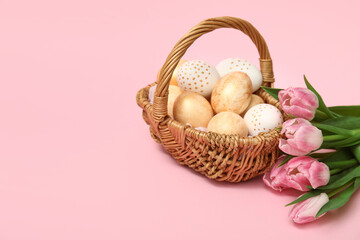 Basket with Easter eggs and tulips on pink background