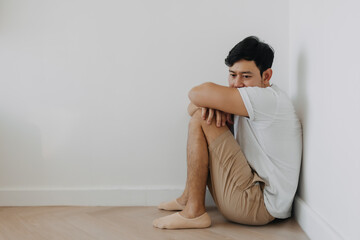 Lonely depressed asian man sit at the corner of the room.