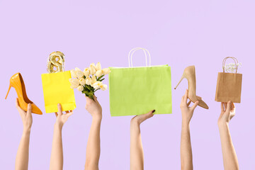 Female hands with high heel shoes, shopping bags and tulips on lilac background. International Women's Day
