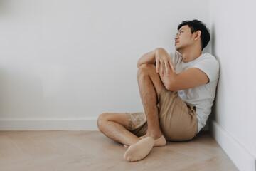 Lonely depressed asian man sit at the corner of the room.