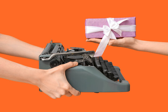Female hands with retro typewriter and gift box for International Women's Day on color background, closeup