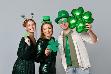 Happy friends with clovers on light background. St. Patrick's Day celebration