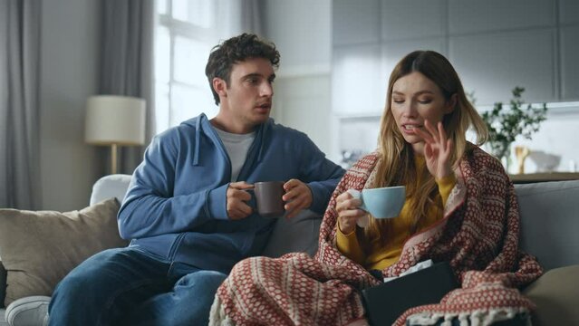 Affectionate man caring sick girlfriend at living room. Lady drinking beverage