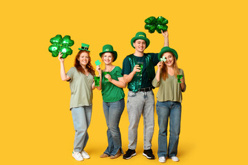 Group of people with beer and clovers on yellow background. St. Patrick's Day celebration