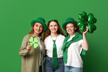 Beautiful women with clovers on green background. St. Patrick's Day celebration